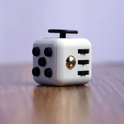 Fidget Cube Toy shown in white and black color combination featuring multiple interactive sides with buttons, switches, and a spinner on wooden surface, perfect for stress relief and sensory play